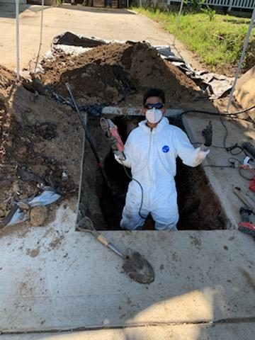 Bryan of Next Level Plumbing suited up and working in a sewer-line excavation