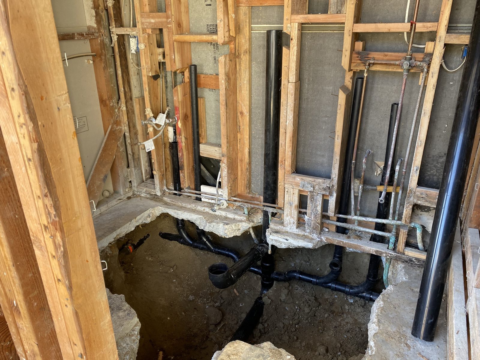 Whole-house repipe in progress: new drain and water lines through open framing